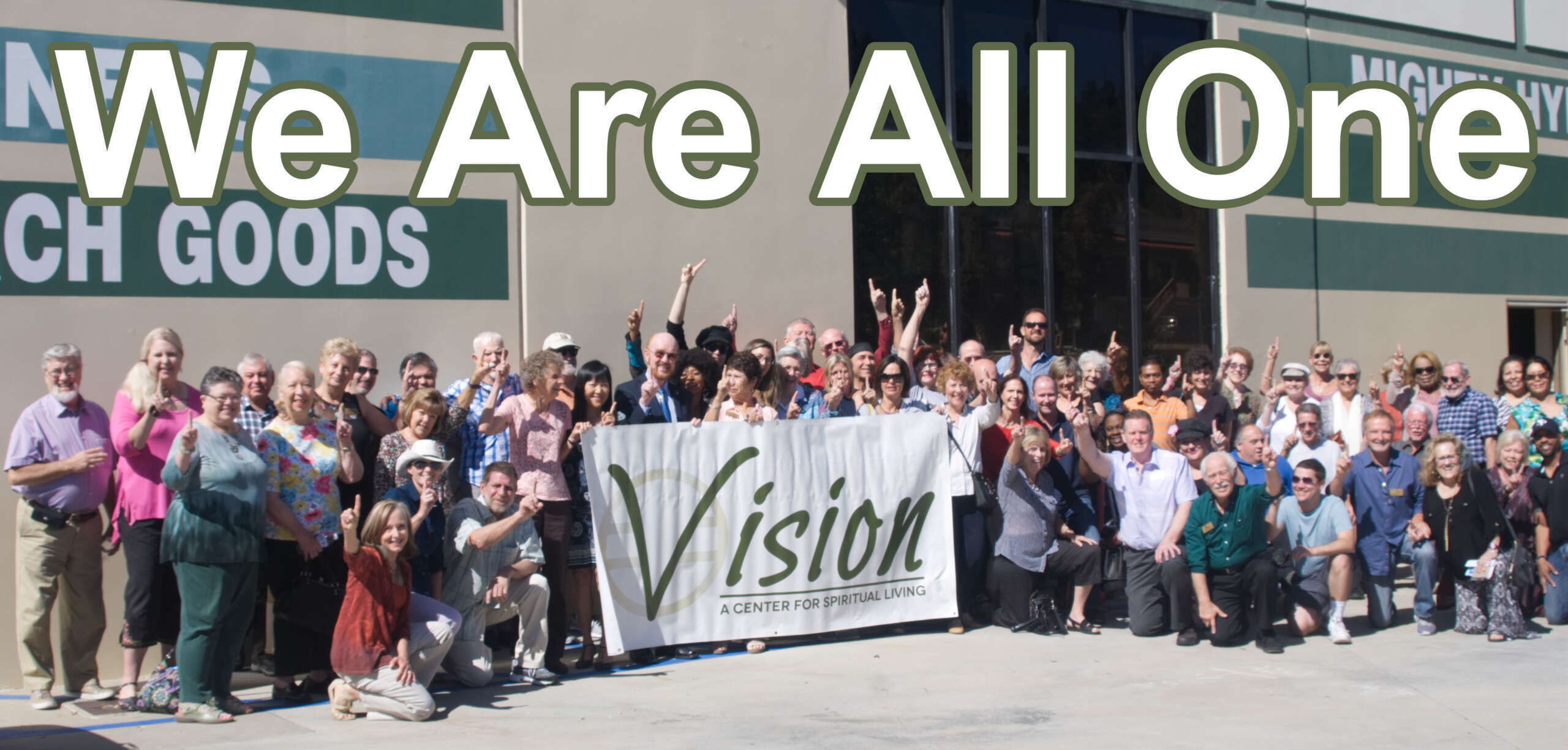 Large group holding a 'Vision' banner, posing for a photo outdoors.