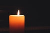 A single lit candle glowing softly in the dark.