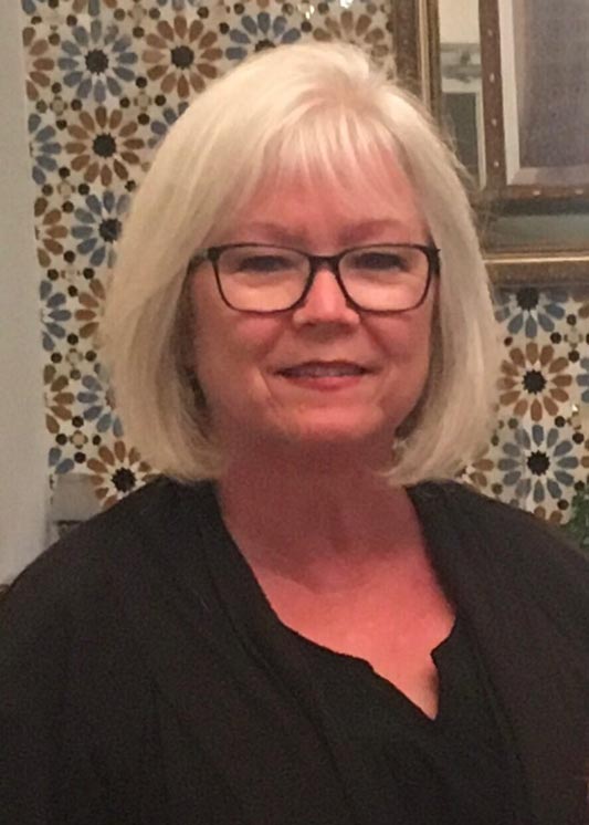 Woman smiling in front of patterned wall.