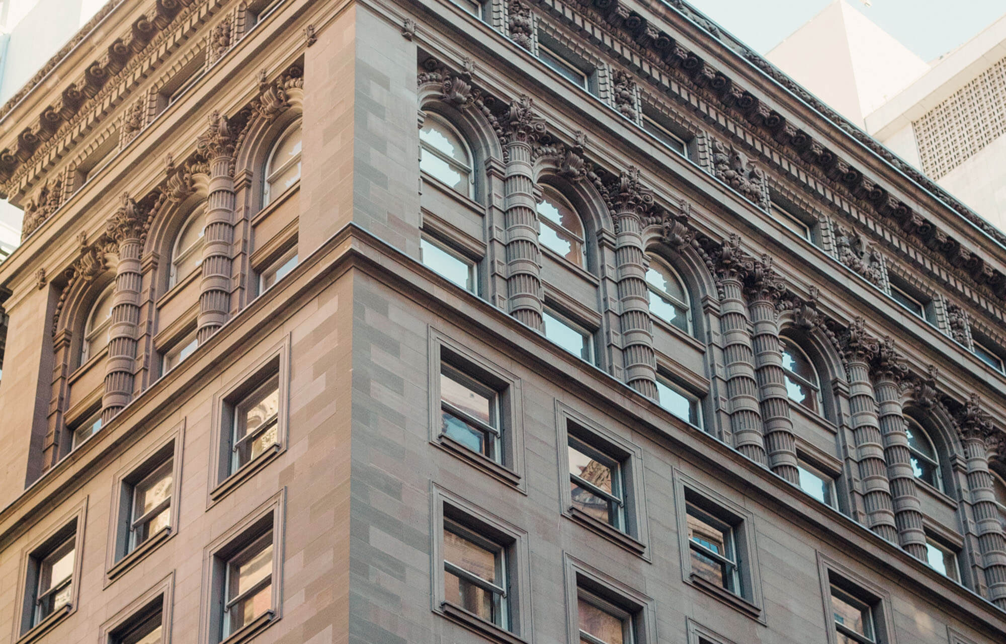 Ornate historic building corner with detailed Corinthian columns and arched windows.
