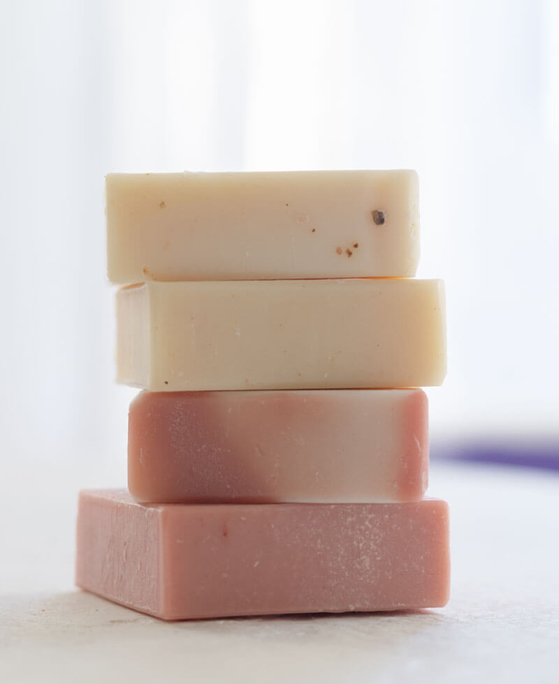 Stack of four assorted handmade soap bars in soft pastel colors.